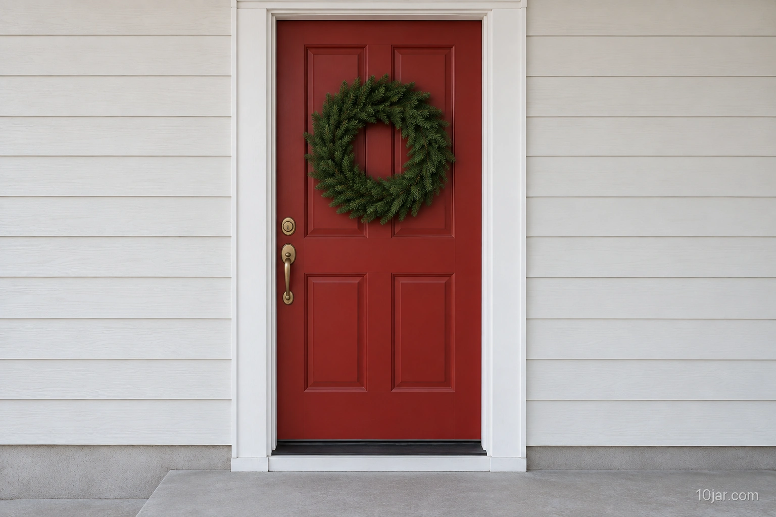 Solid red door with a restrained evergreen wreath centered above fully visible handle and lock hardware