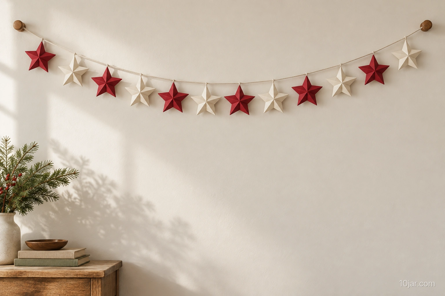 Six-foot garland arranged in a gentle curve with exactly twelve folded red and cream paper stars on a clear indoor wall