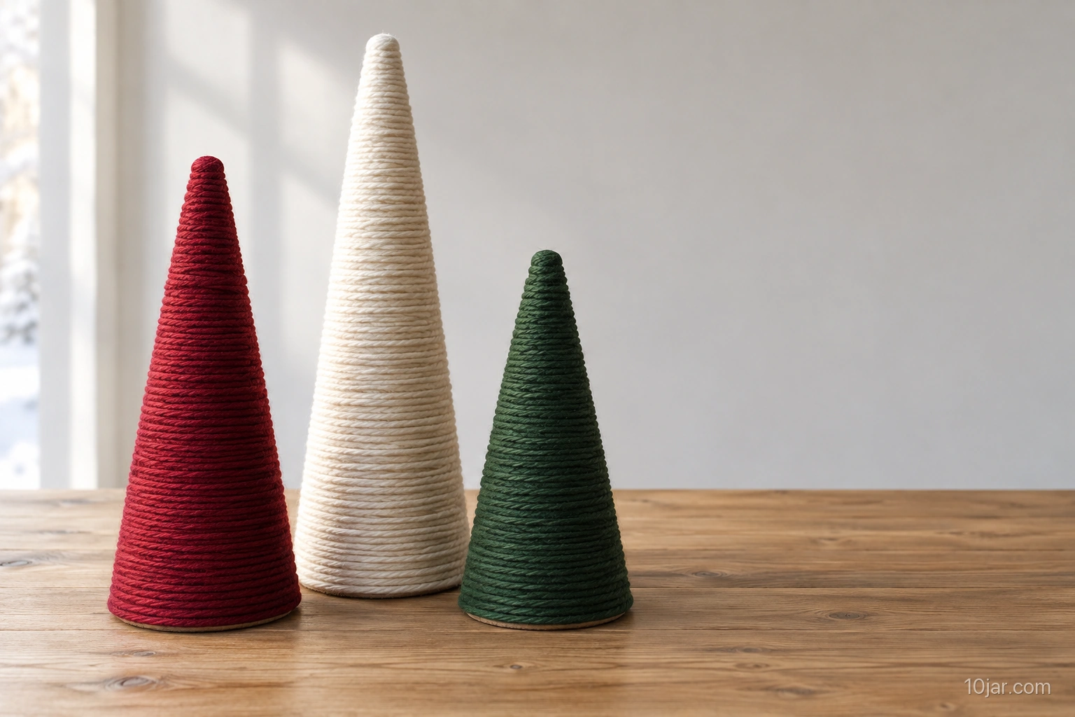 Exactly three freestanding yarn-wrapped cardboard Christmas trees in six nine and twelve inch heights on a dry tabletop