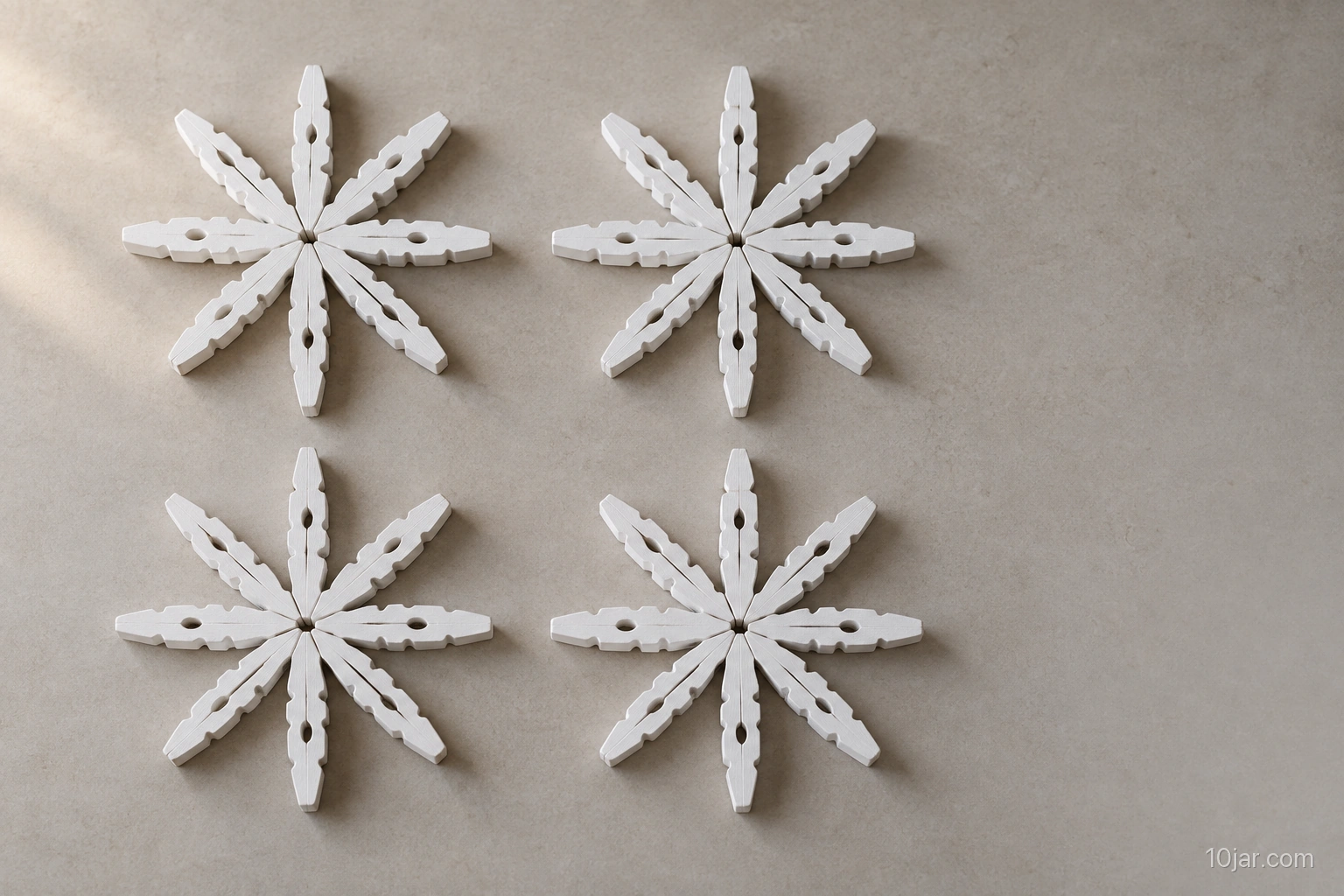 Exactly four white wooden-clothespin snowflakes with eight-piece radial structures resting fully dry on a protected craft table